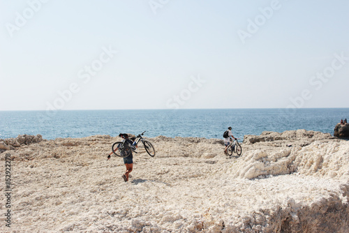 Mountain biking. A cyclist on a rock walks along the sea. MTB cyclist stands on a cliff. photo