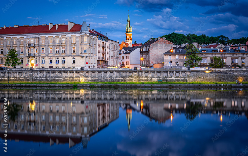 Obraz premium Panorama of Podgorze district in Krakow, Poland with beautiful reflection in Vistula river during blue hour.