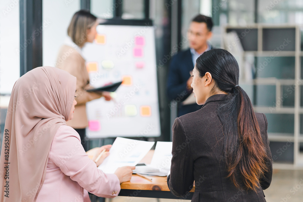 Diverse business team analyzing data and discussing strategies during an office meeting, using documents and a laptop. Diverse business team analyzing data and discussing strategies during an office meeting, using documents and a laptop.