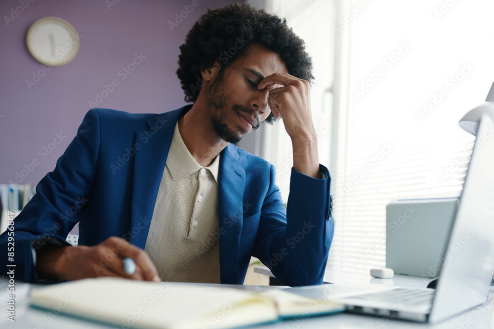 Businessman suffering from headache after working al day long in office Businessman suffering from headache after working al day long in office