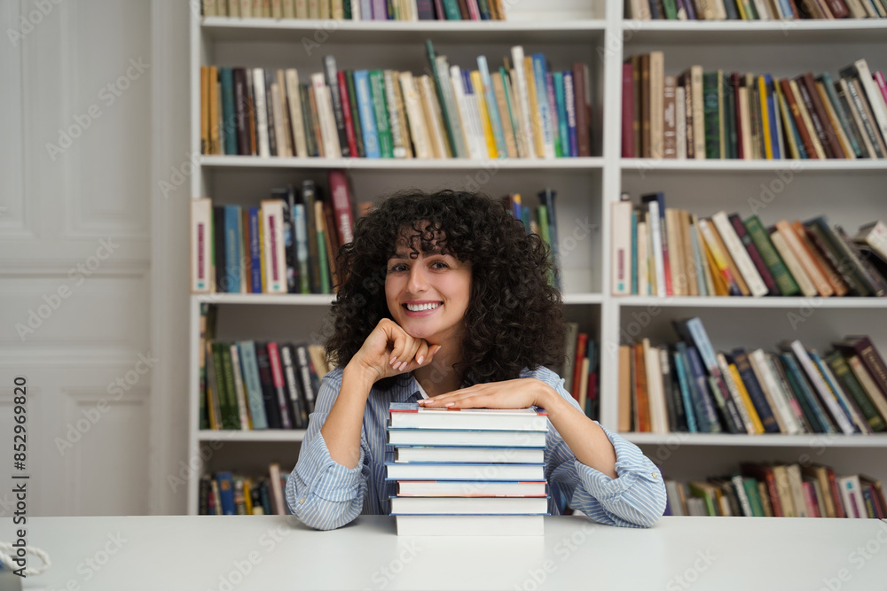 Female student with stack of books sitting at table in library Female student with stack of books sitting at table in library