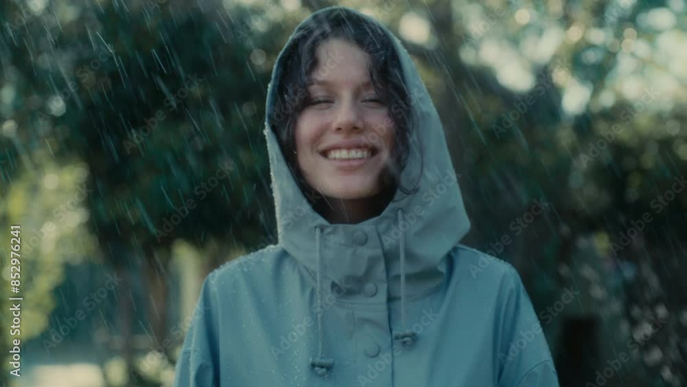 Woman in a rain coat standing outside in the rain and smiling Woman in a rain coat standing outside in the rain and smiling