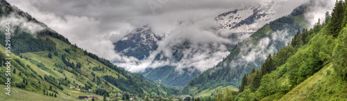 Panoramic view on a rainy day down into the Rauris Valley and onto the cloud-covered, mighty three-thousand-meter mountains such as the “Hocharn” and the “Hohen Sonnblick”. photo