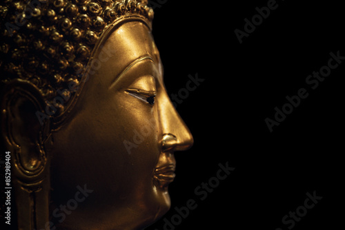 A golden Buddha head on a black background with perfectly placed lights and shadows.
