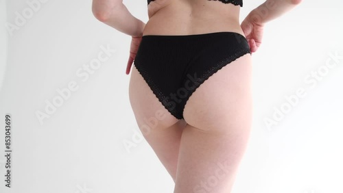 Close-up view of sexy slim caucasian woman standing against grey background. Woman wears black lace panties. Soft focus. Real time video. Fashion and sensuality theme.