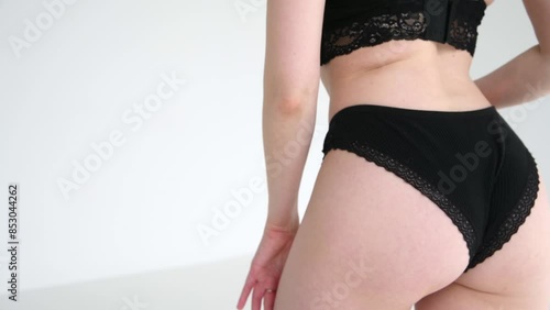 Close-up view of sexy slim caucasian woman standing against grey background. Woman wears black lace panties. Soft focus. Real time video. Fashion and sensuality theme.