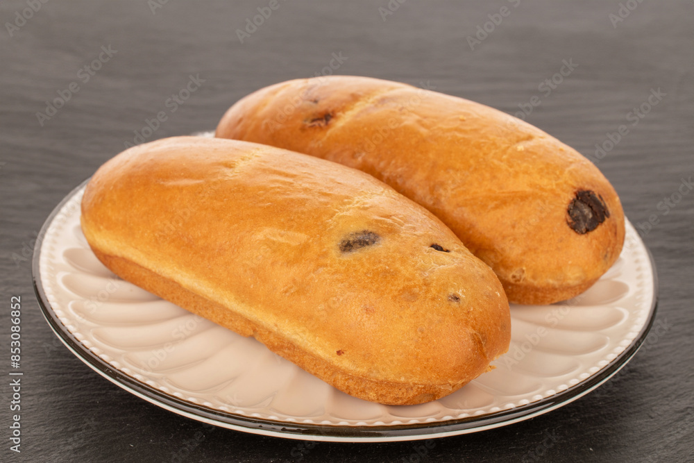Two sweet buns on a ceramic saucer on slate stone, macro. Two sweet buns on a ceramic saucer on slate stone, macro.