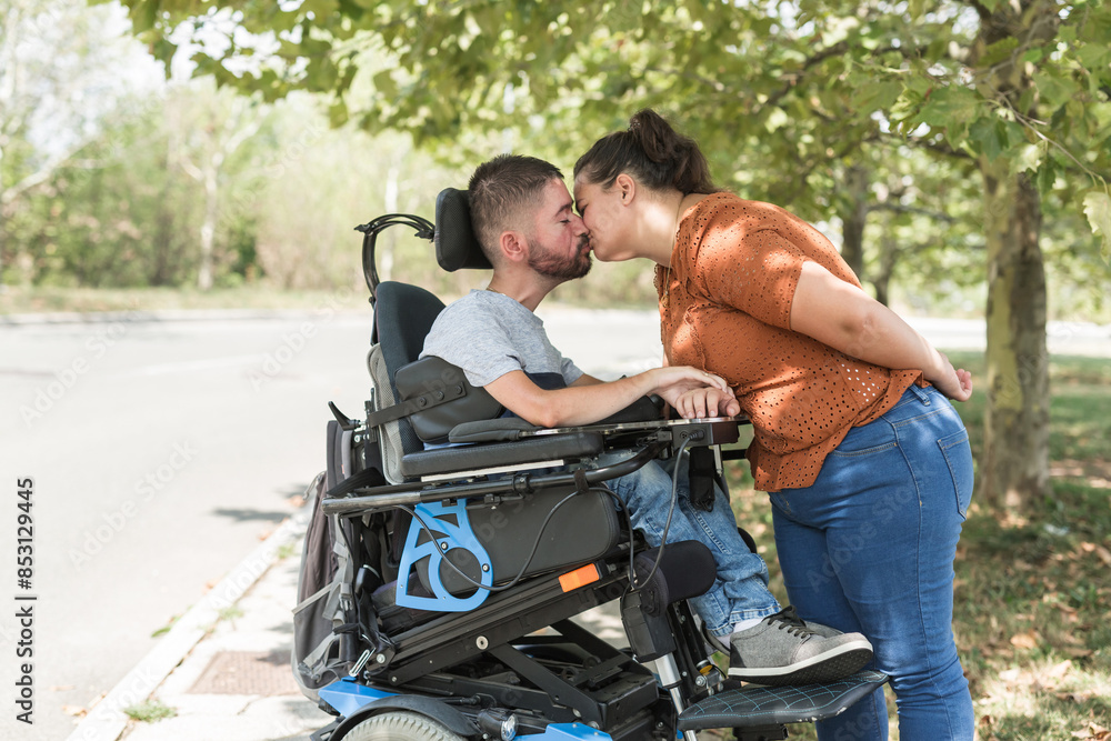 Moment of tenderness, a woman kissing and hugging her husband with a physical disability. Diversity, love, and relationship concepts. Moment of tenderness, a woman kissing and hugging her husband with a physical disability. Diversity, love, and relationship concepts.