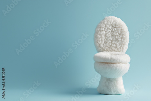A fluffy white plushie loo on a blue background. A soft toy decor toilet.