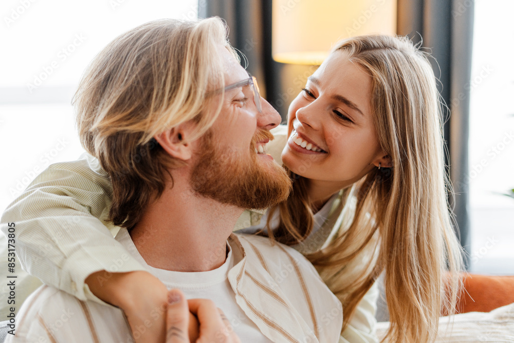 Young woman embracing from behind her boyfriend smiling at home Young woman embracing from behind her boyfriend smiling at home