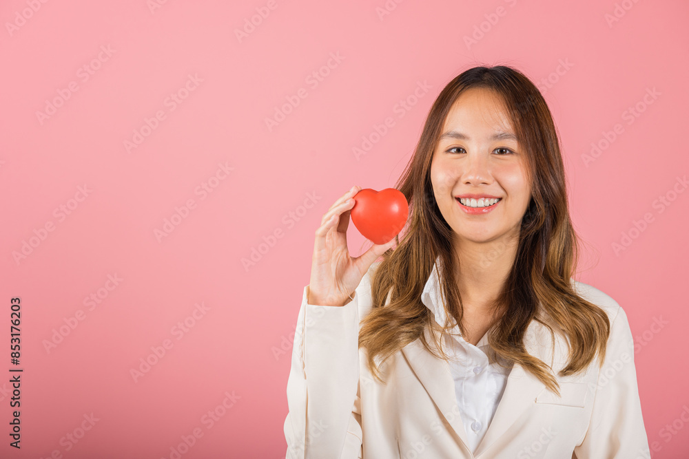 Smiling woman confidence showing holding red heart with her hand palm isolated pink background, Asian happy portrait beautiful young female send love and happy valentine in studio shot, copy space Smiling woman confidence showing holding red heart with her hand palm isolated pink background, Asian happy portrait beautiful young female send love and happy valentine in studio shot, copy space
