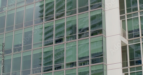 Exterior of contemporary high-rise office building. Floor-to-ceiling glass windows. Concept of modern architecture, corporate environment, and urban skyline. Urban background.