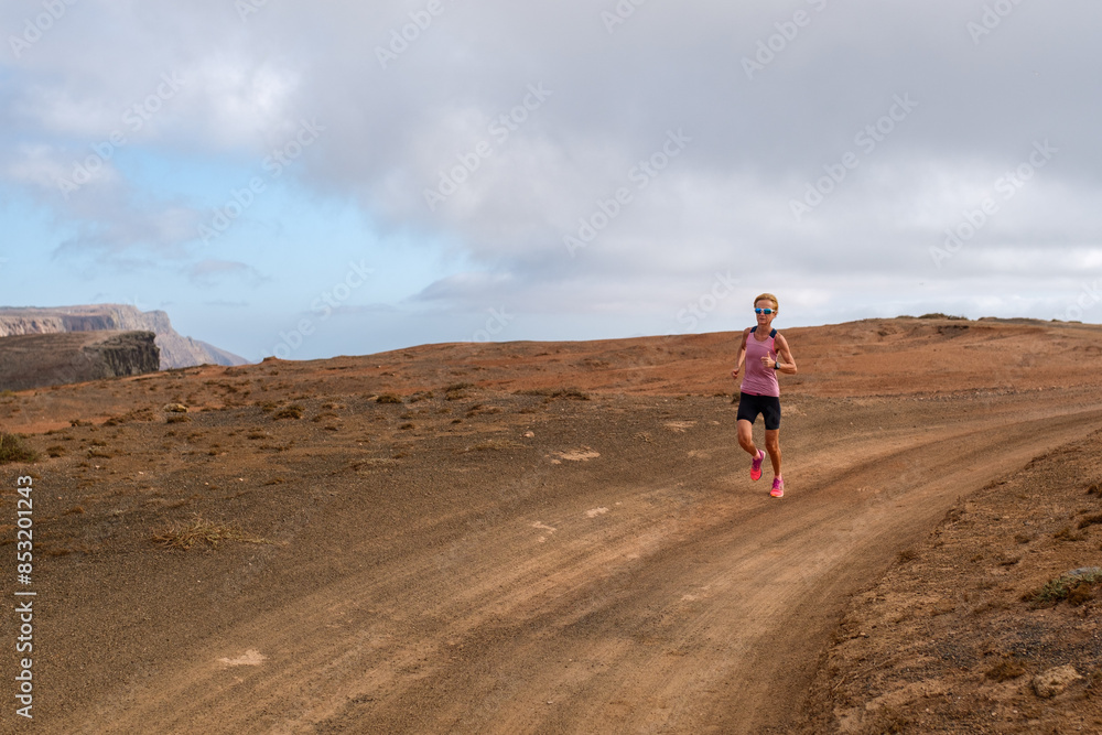 Woman running on dirt path in vast desert landscape Woman running on dirt path in vast desert landscape