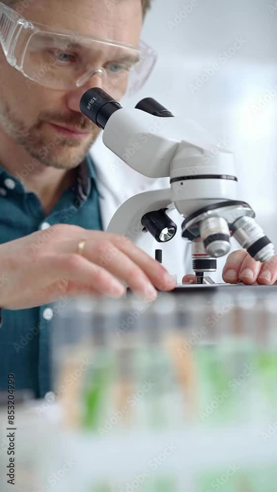 Man scientist with protective glasses using microscope in laboratory. Microbiology science concept Man scientist with protective glasses using microscope in laboratory. Microbiology science concept