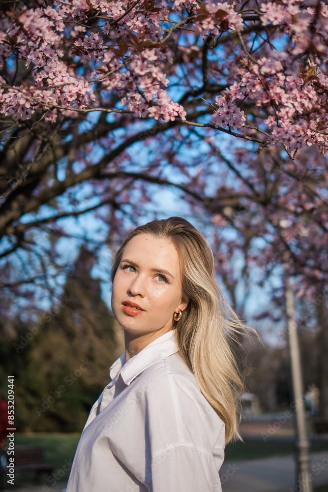 Woman with cherry flowers surrounded by blossoming trees copy space. Beauty and seasonal change and spring bloom season concept. Woman with cherry flowers surrounded by blossoming trees copy space. Beauty and seasonal change and spring bloom season concept.
