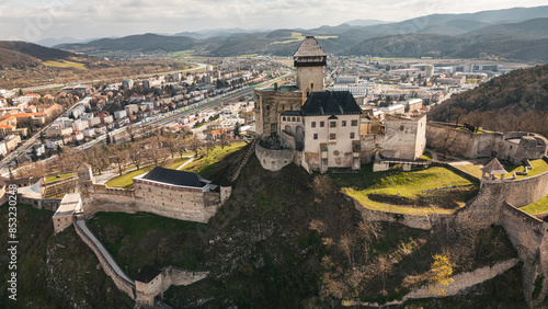 Aerial panoramic view of medieval Trenciansky hrad and Trencin town in Slovakia. Overhead high angle scene of old buildings, stone walls and towers of romantic castle, historic museum on rocks photo