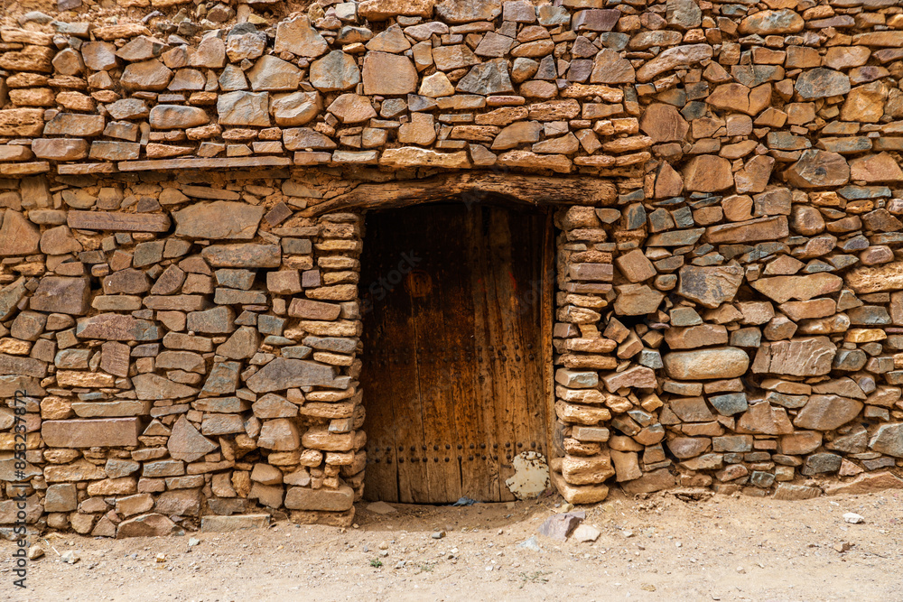 Fototapeta premium door of an old castle and architecture of stones buildings in a village in the south of the Kingdom of Morocco in the Souss-Massa region