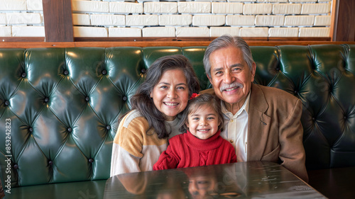 Two latino grandparents with their granddaughter. Older mexican woman and her husband sitting with their granddaughter in a restaurant. a family of three sitting at a table in a restaurant.