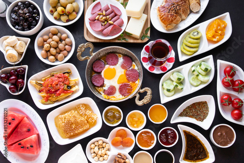 Fresh Traditional Turkish Breakfast on the black surface with copper egg pan and white plates © Gulsen