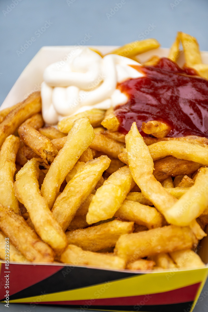 Belgian street and fast food, paper box in colors of Belgian flag with fried potato frit chips and ketchup and mayonnaise sauсe Belgian street and fast food, paper box in colors of Belgian flag with fried potato frit chips and ketchup and mayonnaise sauсe