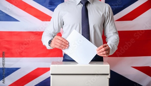 Close up body of a man standing behind the ballot box with his hand inserting a ballot against the blurred background of the British flag. British General elections photo