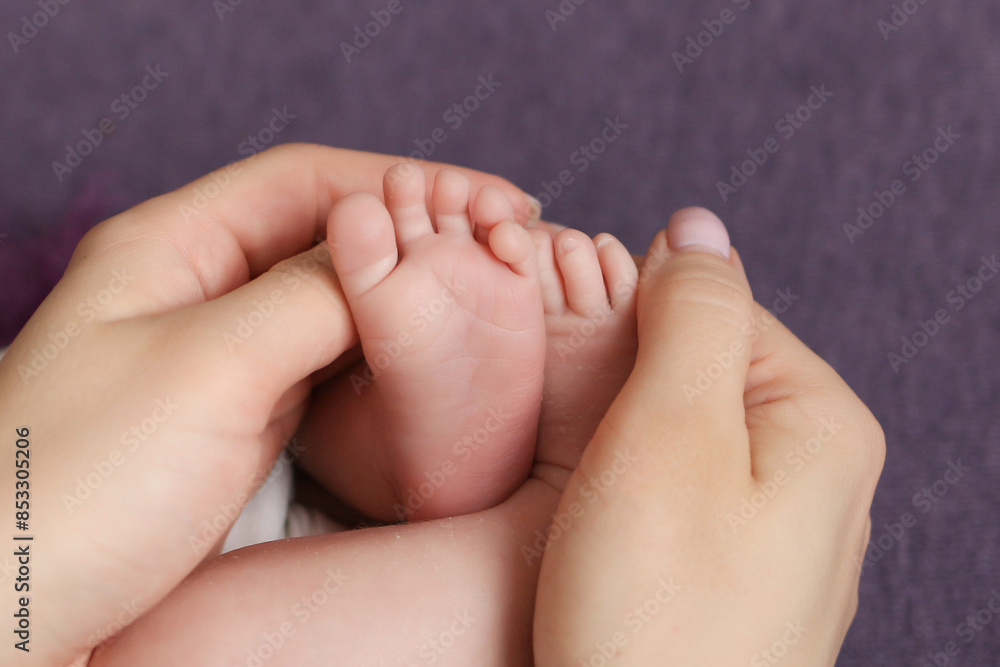 the parent's hand holds the baby's small leg, light close-up photo. family concept. background with place for text. the parent's hand holds the baby's small leg, light close-up photo. family concept. background with place for text.