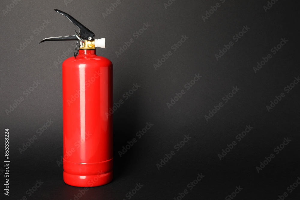 Obraz premium One red fire extinguisher on dark gray background, space for text