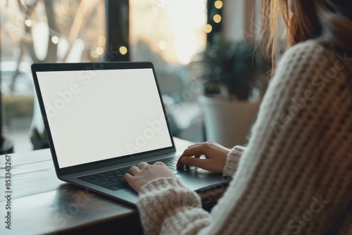 Close up of a unrecognizable Woman typing on a laptop with a blank screen on the desk, copy space. no face  photo