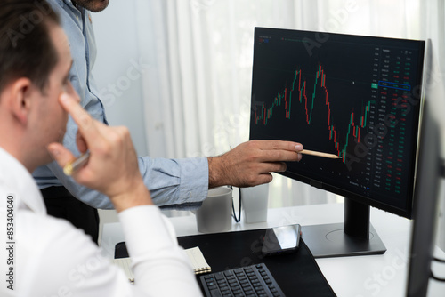 Stock trader pointing highest stock market to present coworker on dynamic valued analysis research on real time monitor screen, cooperating business investment in financial company exchange. Sellable.