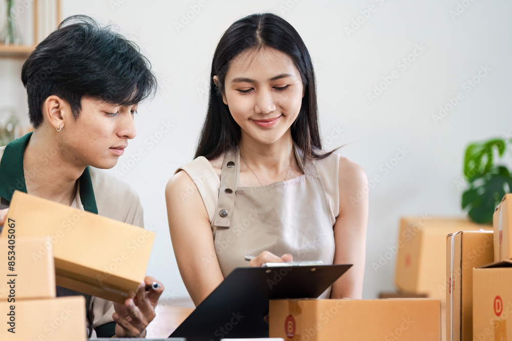 Young entrepreneur Working Together in a Modern Small Business Office Surrounded by Shipping Boxes and Documents. small business, e-commerce, e-business concept Young entrepreneur Working Together in a Modern Small Business Office Surrounded by Shipping Boxes and Documents. small business, e-commerce, e-business concept