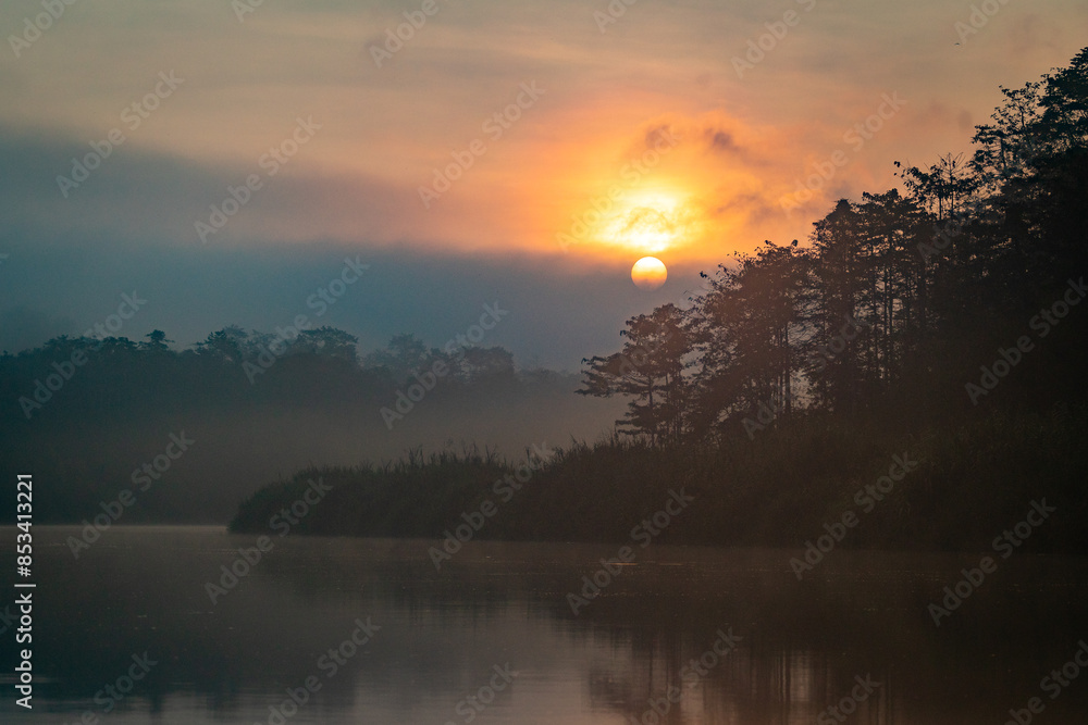 Obraz premium Sunrise above a remote wilderness rainforest and river in the jungles of Borneo