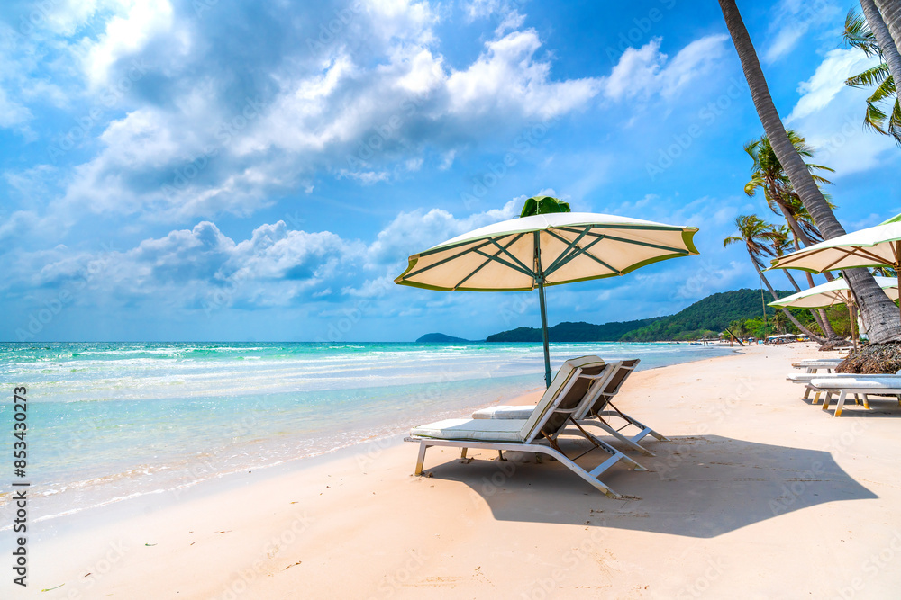 Fototapeta premium Sunbeds under tropical palms on beach on Phu Quoc island, Vietnam. Beach's smile