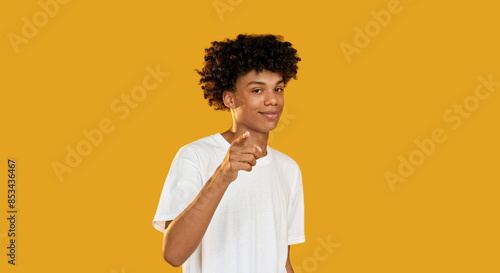 You pointing. Encouraging gesture. Confident smiling guy supporting showing approval isolated on yellow empty space background. photo