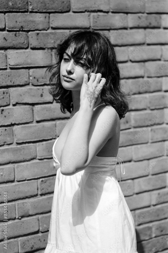 A nostalgic portrait of young woman posing in front of brick wall. A nostalgic portrait of young woman posing in front of brick wall.