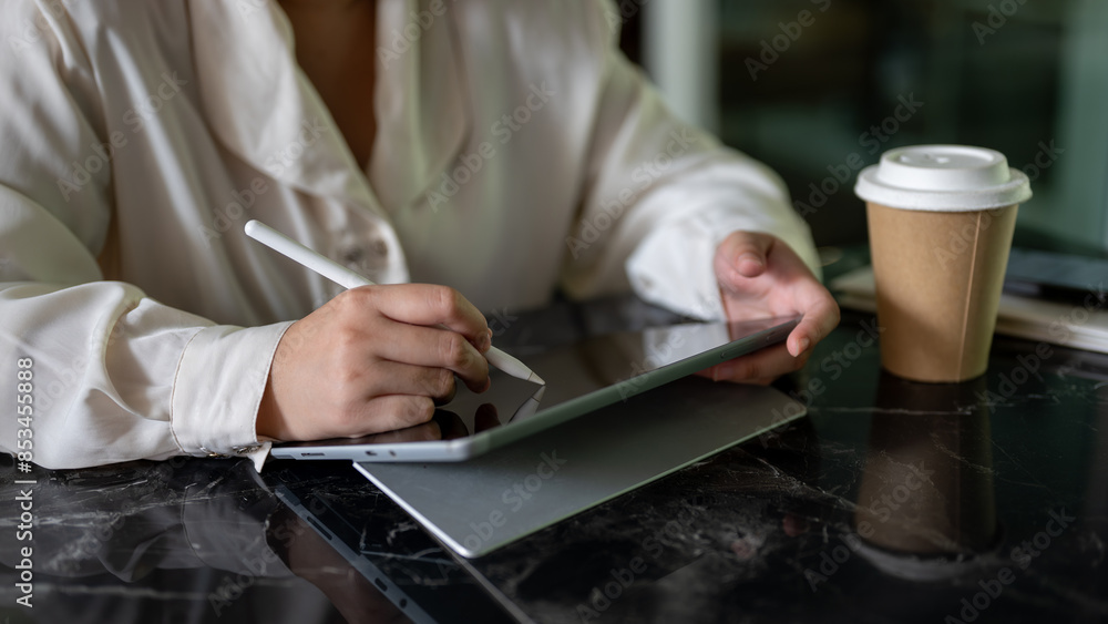 A cropped image of a businesswoman holding a stylus pen, writing on her digital tablet. A cropped image of a businesswoman holding a stylus pen, writing on her digital tablet.