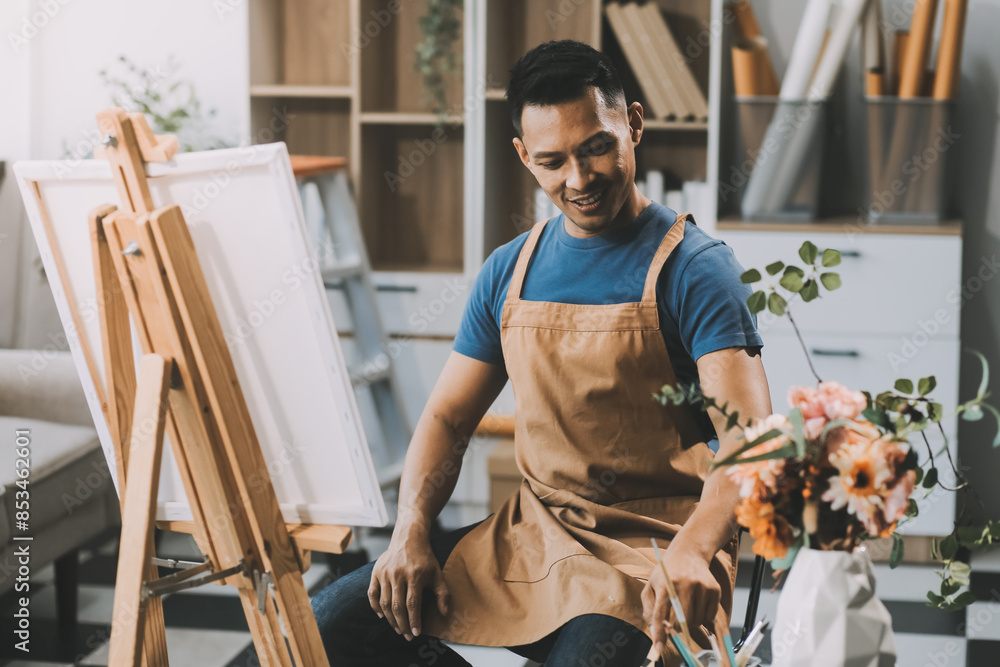 Fototapeta premium Young male artist painting picture in studio