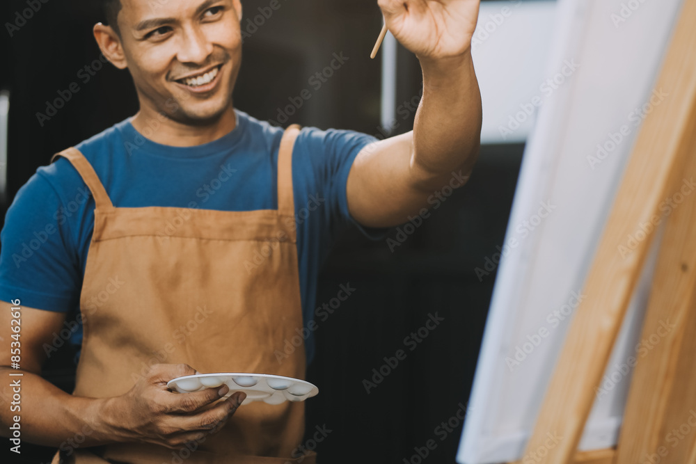Young male artist painting picture in studio Young male artist painting picture in studio