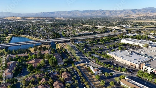 Aerial view of a suburban area with a highway, residential buildings, and a small lake in San Jose