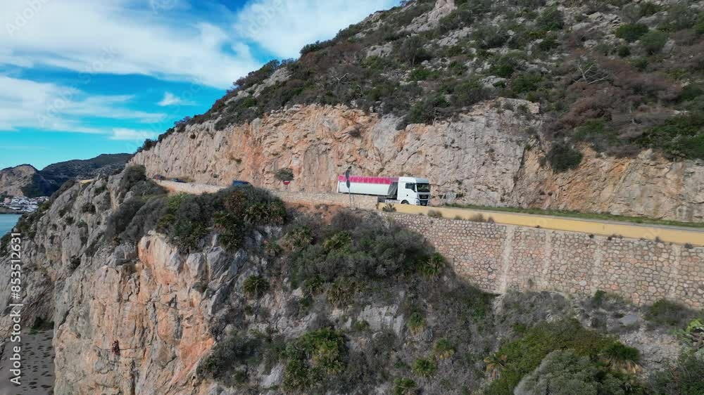 Truck driving a scenic coastal road along rocky cliffs overlooking the ocean in Port of Ginesta, Barcelona Truck driving a scenic coastal road along rocky cliffs overlooking the ocean in Port of Ginesta, Barcelona