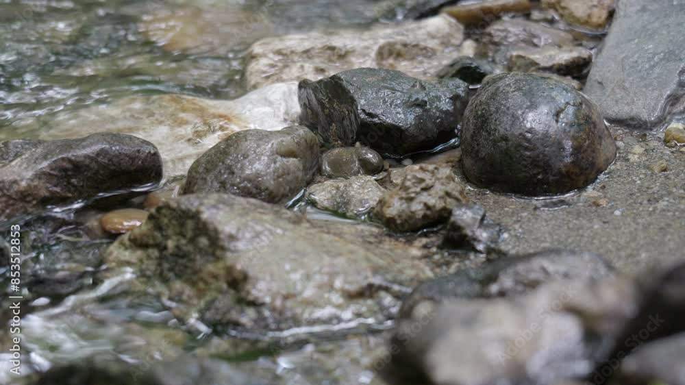 Gently rippling water in a mountain stream with dark stones. Gently rippling water in a mountain stream with dark stones.