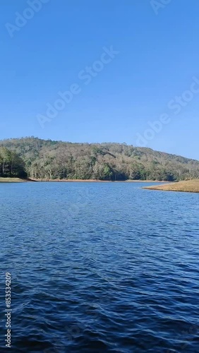 Boating on a blue periyar lake in kerala, india. Periyar Tiger Reserve offers 1.5 hrs boating trips at the lake near the sanctuary. Blue travel background having water, forest and sky in a sunny day photo