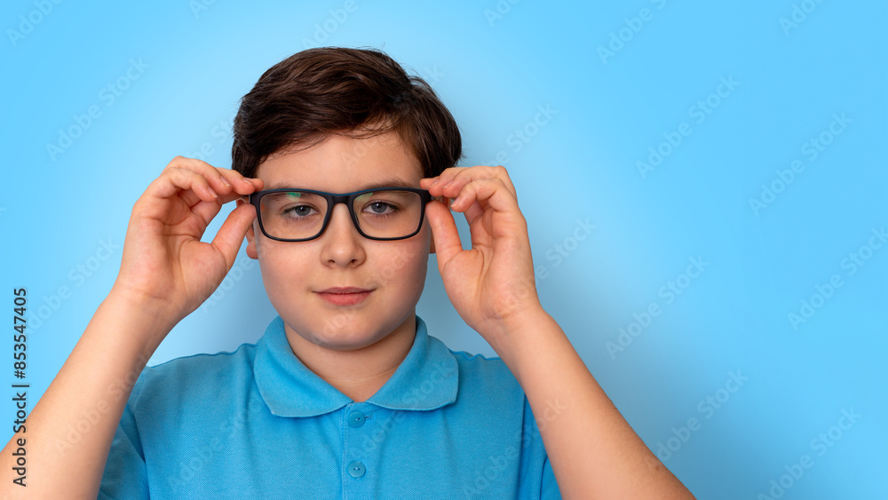 Close up of dark haired boy in glasses on light-blue background, look at camera Close up of dark haired boy in glasses on light-blue background, look at camera