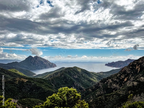 Panorama einer Küste auf Korsika, mit Bergen, Meer und dramatischen Wolken 