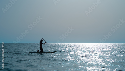 Photography silhouette of person doing sup surfing on the sunset in the blue sea