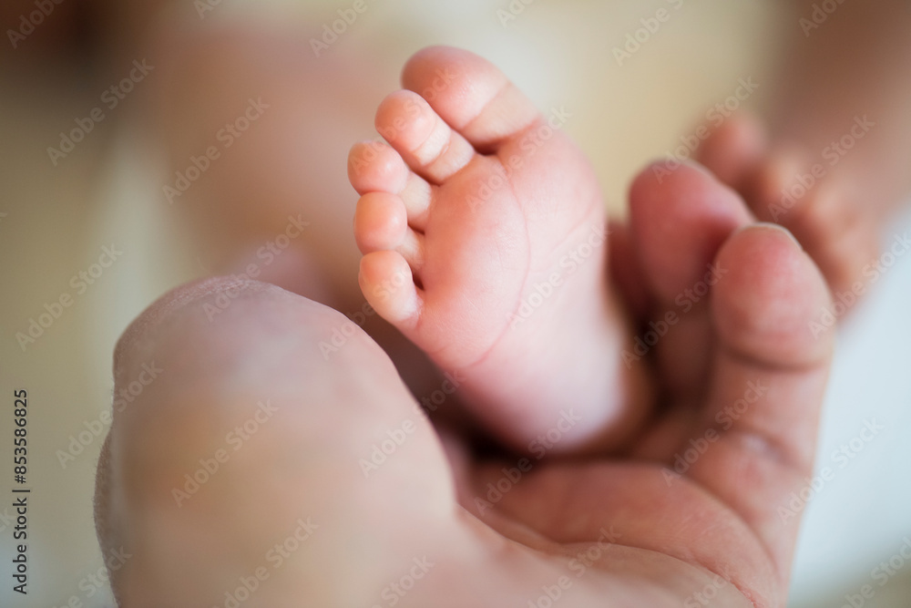 Parent holding small feet of little baby lying on bed. Parent holding small feet of little baby lying on bed.