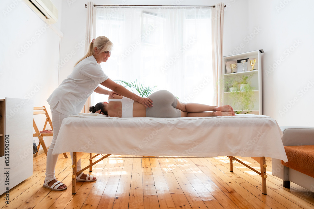 Chiropractor treating teenage patient lying on table for chiropractic adjustment of back in rehabilitation center Chiropractor treating teenage patient lying on table for chiropractic adjustment of back in rehabilitation center