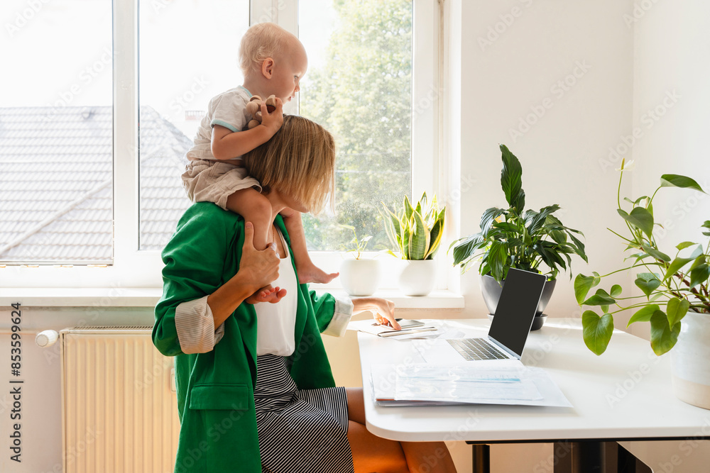 Freelancer mother carrying son on shoulders and working at home Freelancer mother carrying son on shoulders and working at home