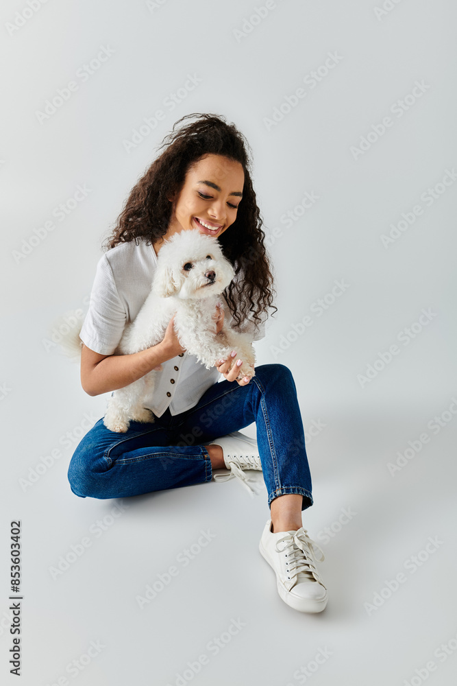 A woman peacefully sits on the floor, tenderly holding her white dog. A woman peacefully sits on the floor, tenderly holding her white dog.