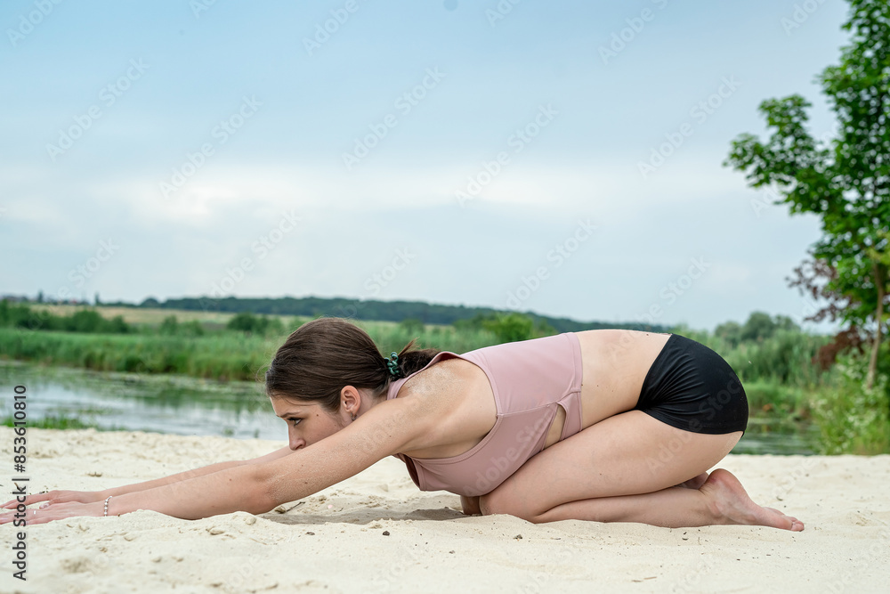 young fitness woman doing streching exercise on lake beach in summer young fitness woman doing streching exercise on lake beach in summer