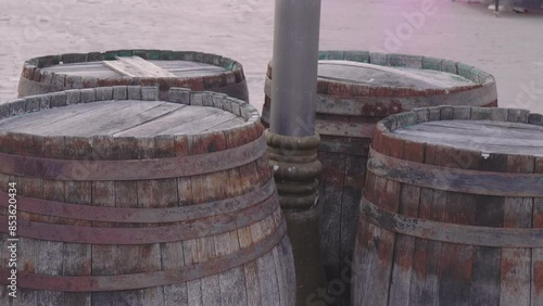 Old barrels with rusty rims stand around a pole on the street. Bondar craftsmanship and winemaking. photo